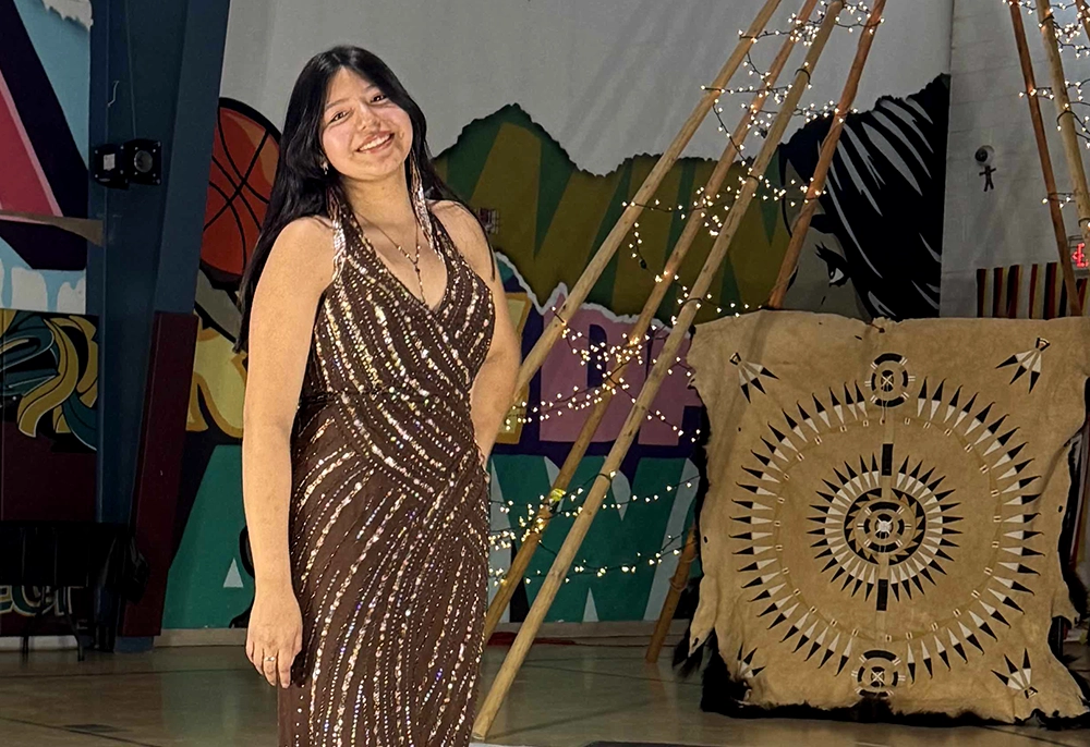 Young Native woman in formal gown smiling with self assurance in front of Lakota art background